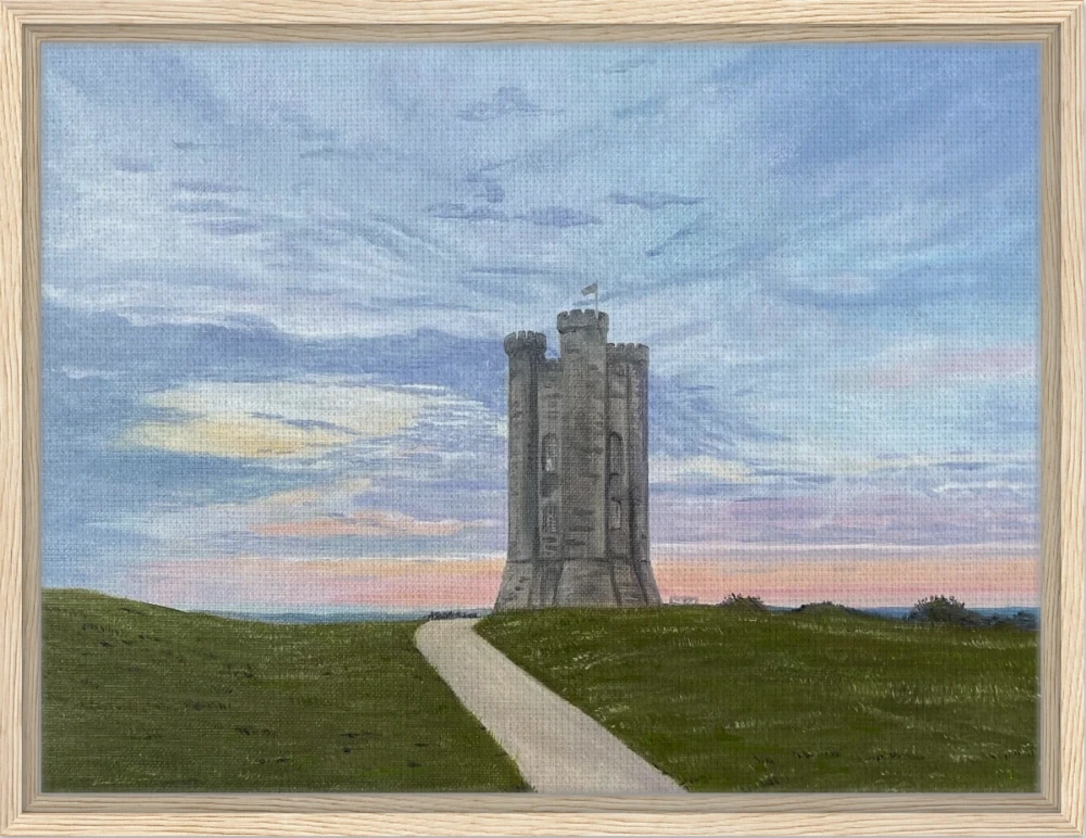 A framed landscape art print depicting Broadway tower on a grassy hill under a blue and pink sky, shown against a white background.
