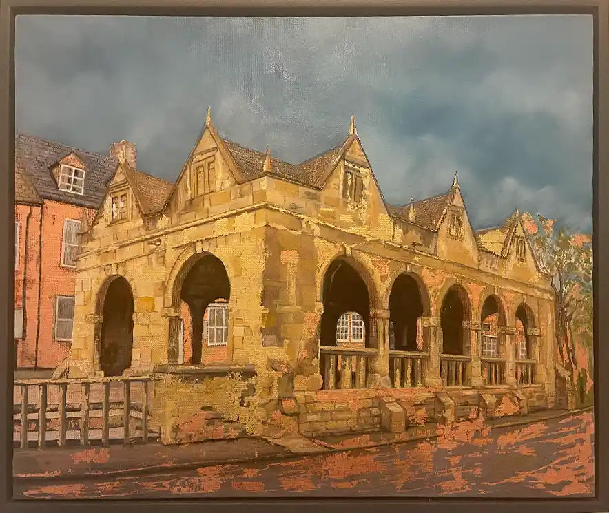 A framed oil painting depicting a historic stone building with arches under a dramatic cloudy sky, rendered in warm gold and bronze leaf 