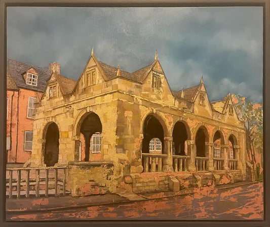 A framed oil painting depicting a historic stone building with arches under a dramatic cloudy sky, rendered in warm gold and bronze leaf 