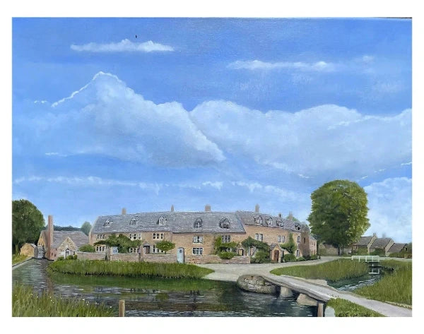 A painted landscape scene showing a large stone cottage beside a canal or stream, with a small bridge in the foreground, grassy banks, trees, and a bright blue sky with large white clouds.