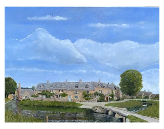 A painted landscape scene showing a large stone cottage beside a canal or stream, with a small bridge in the foreground, grassy banks, trees, and a bright blue sky with large white clouds.