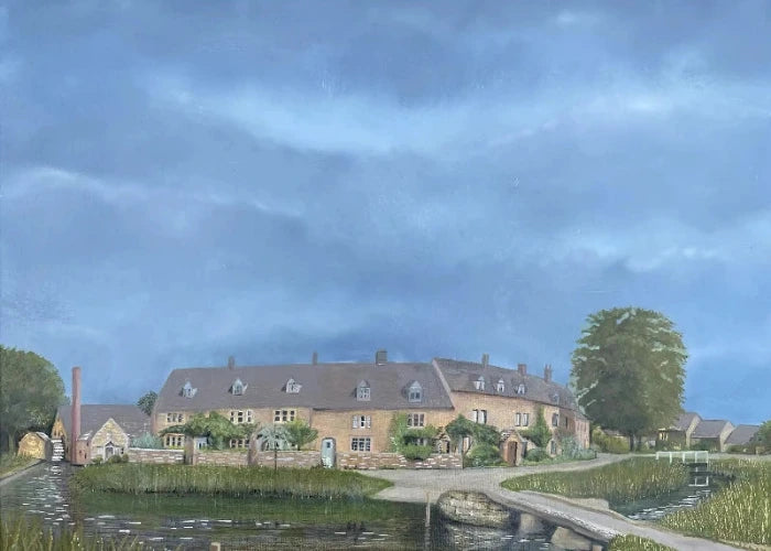 A painted rural scene showing a large stone building with a dark roof beside a canal or pond, with a bridge in the foreground, trees, and a dramatic blue cloudy sky.